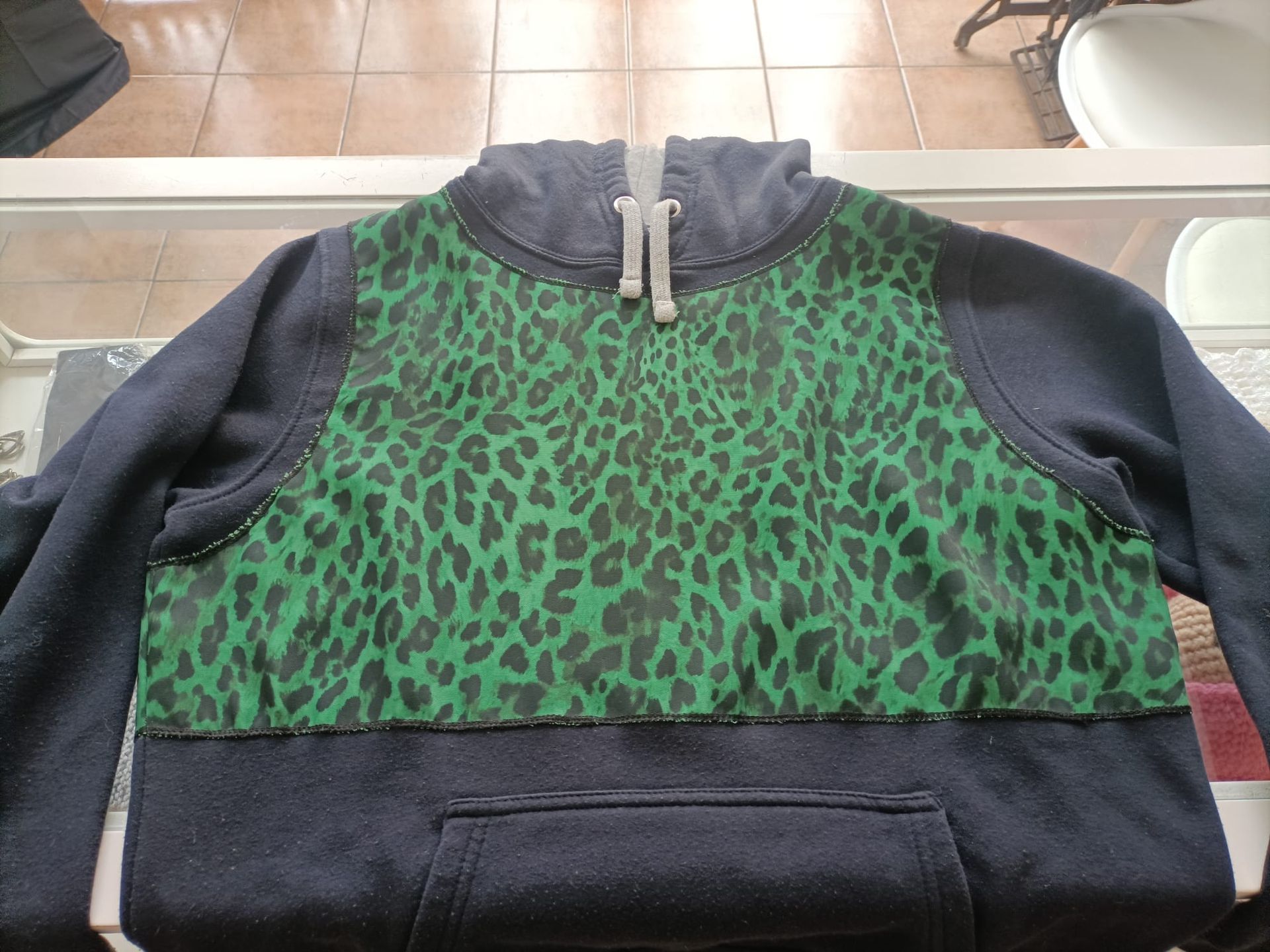 Una sudadera con capucha azul marino oscuro que presenta un llamativo panel con estampado de leopardo verde en el pecho y la capucha.