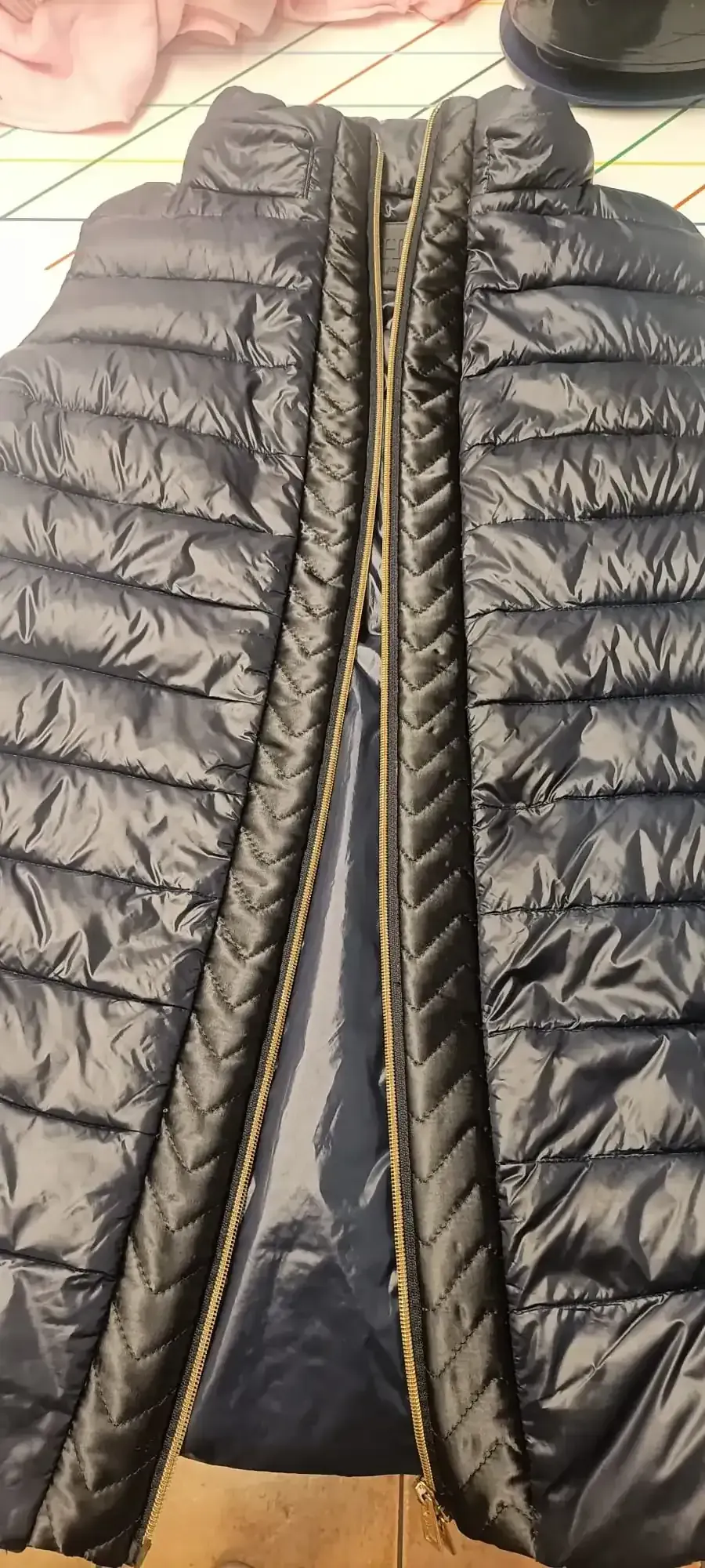 Un chaleco acolchado azul marino visto desde el frente, con una cremallera central visible que recorre toda su longitud.