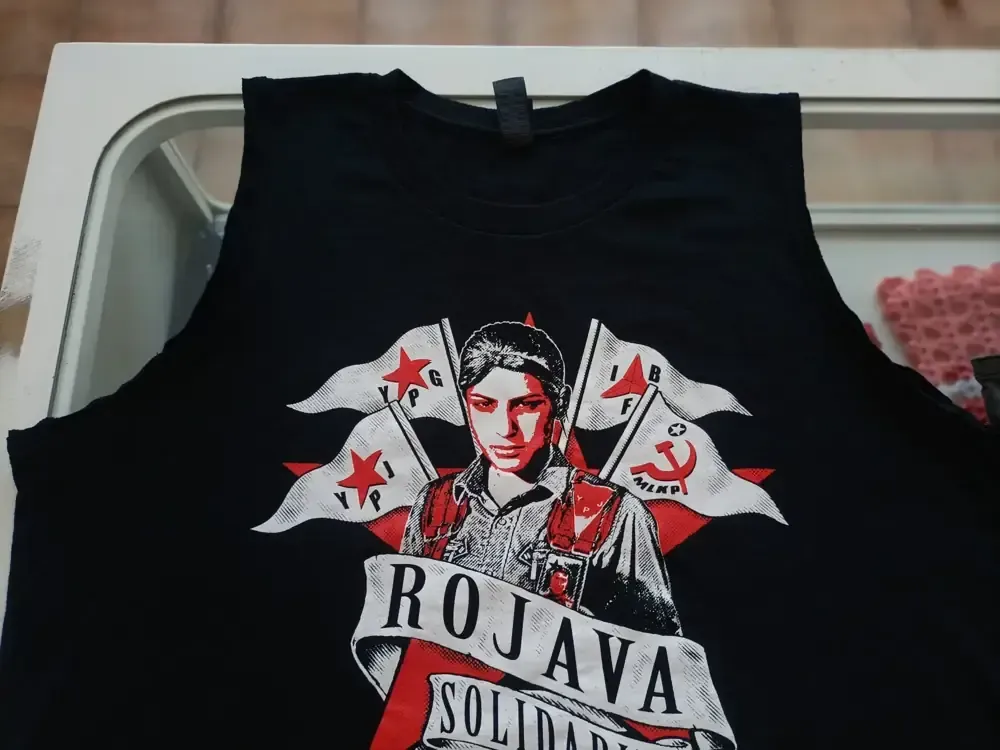 Una camiseta sin mangas negra con la imagen de una persona, banderas y el texto