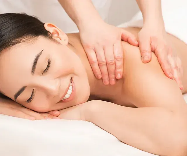 Una mujer sonríe mientras recibe un masaje en un spa.