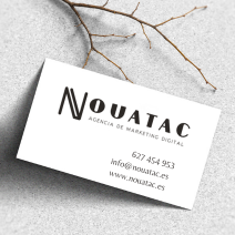 Una tarjeta de presentación de Nouatac está sobre una mesa al lado de una rama.