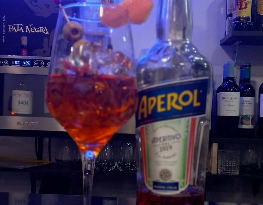 Una botella de Aperol junto a un vaso de Aperol