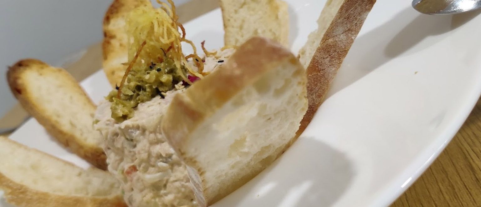 Un primer plano de un plato de comida con pan y una cuchara sobre una mesa.