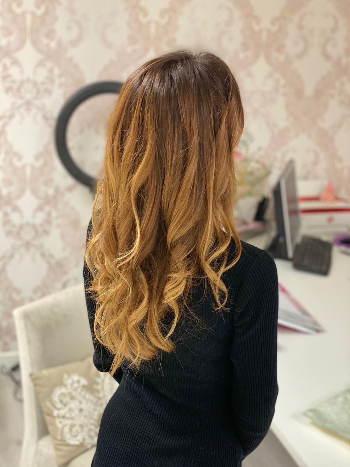 Una mujer con cabello largo y rubio está parada frente a un escritorio.
