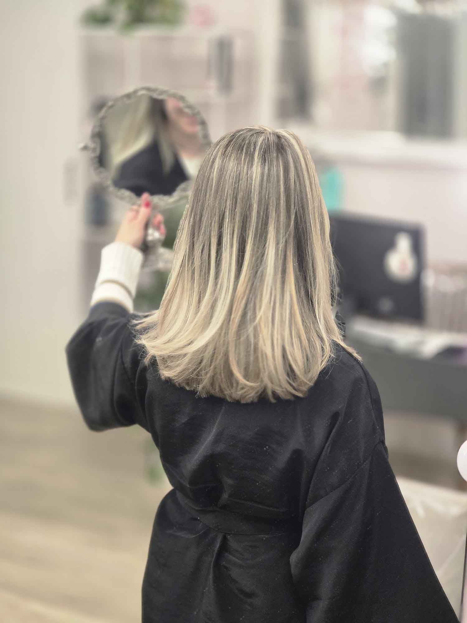 Una mujer se mira el cabello en un espejo.