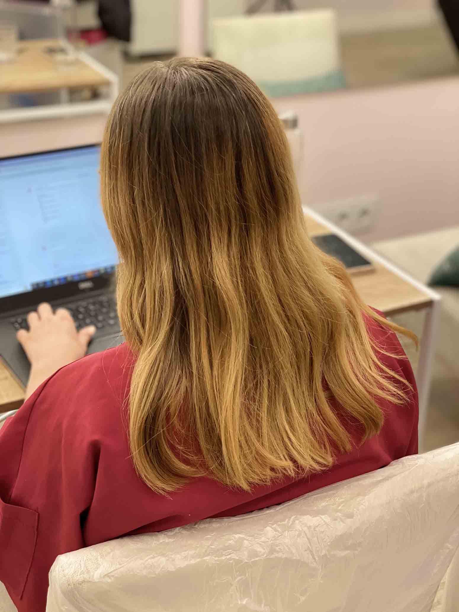 Una mujer está sentada frente a una computadora portátil.