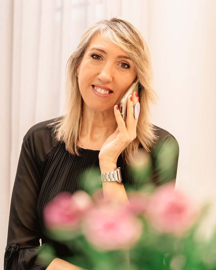 Una mujer está hablando por un teléfono celular frente a flores.