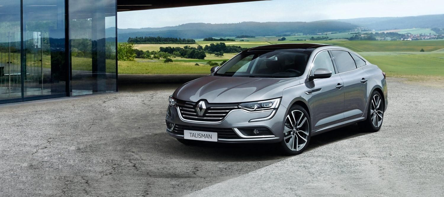 Une berline Renault Talisman garée à côté d'une maison moderne, à la campagne.