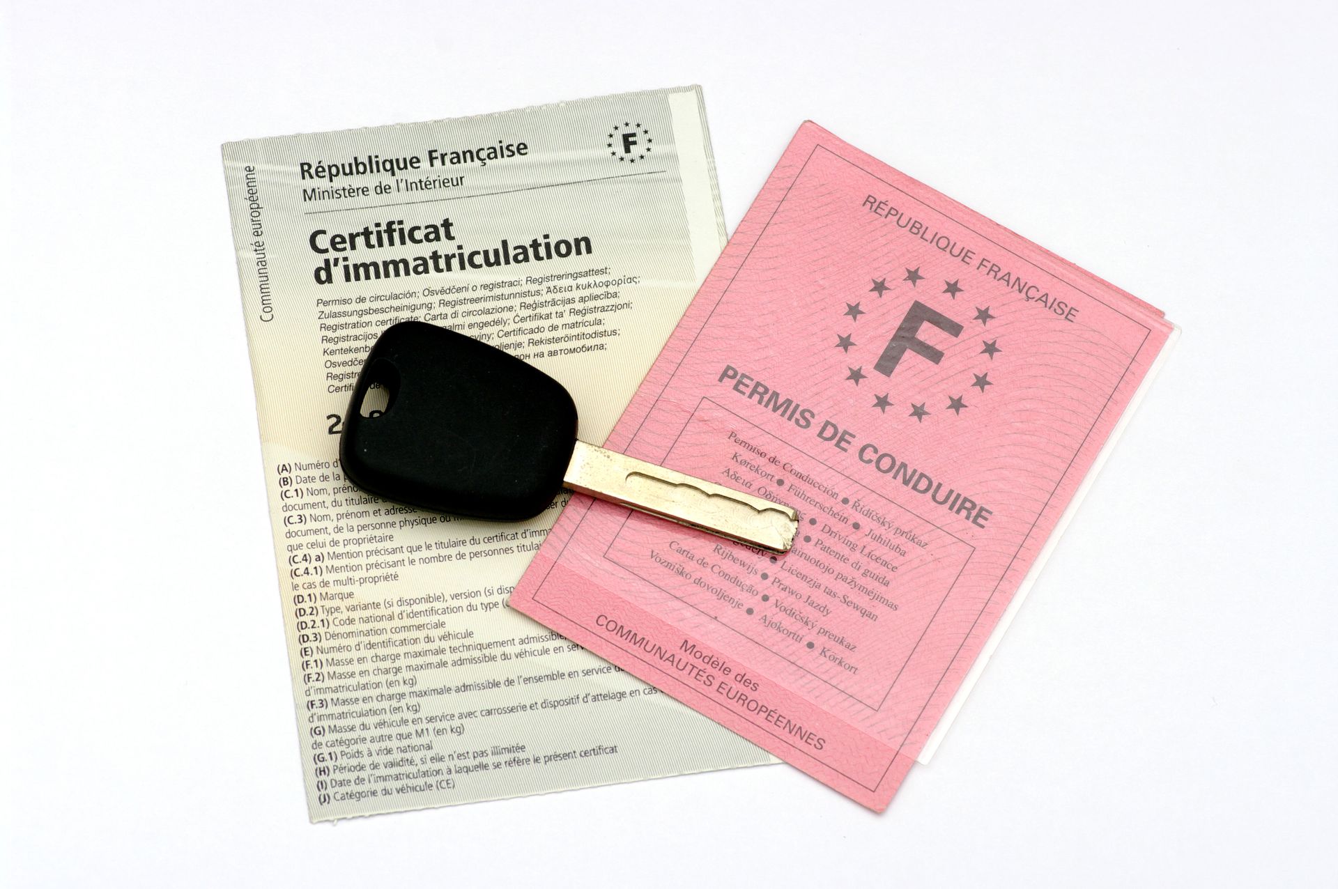 Clé de voiture sur une carte grise et un ancien permis de conduire.