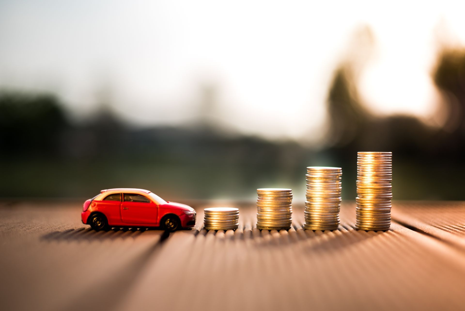 Voiture miniature rouge à côté de piles de pièces de monnaie sur une table.