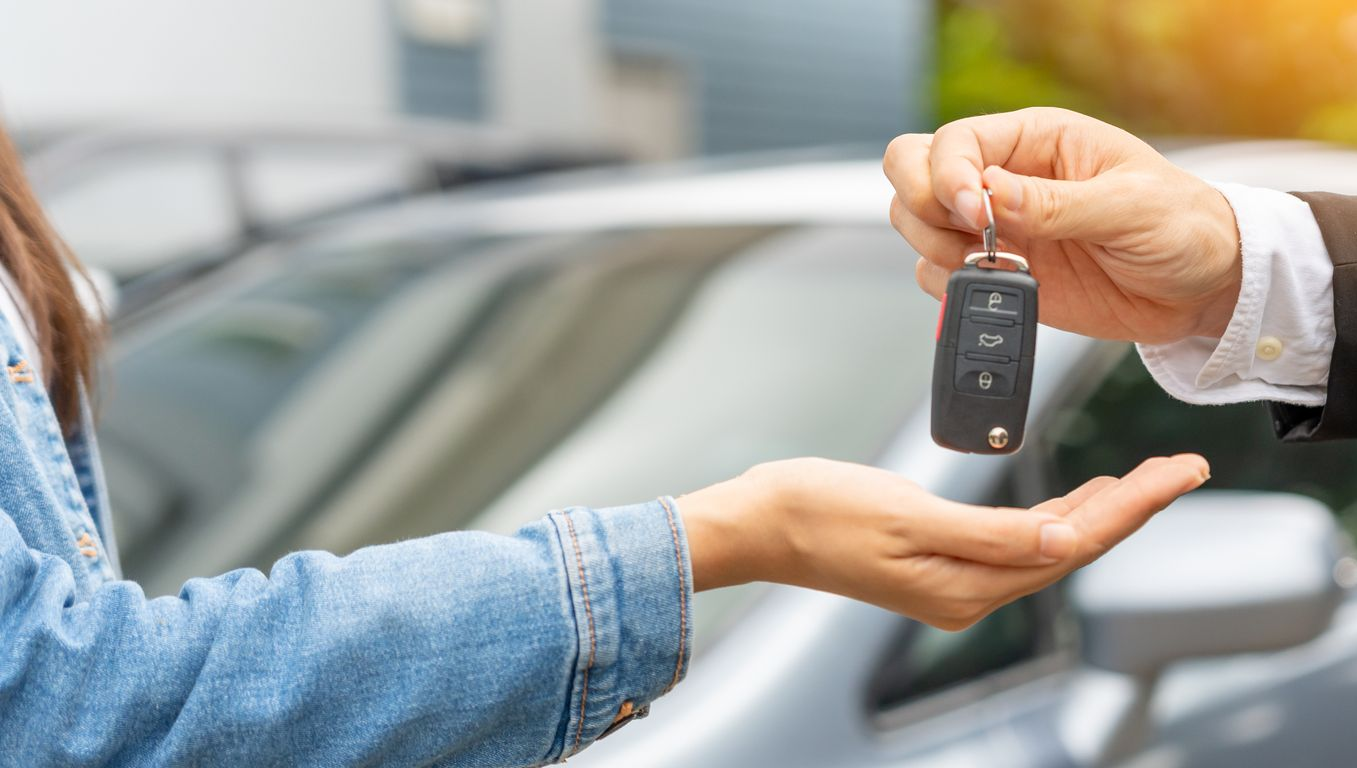 Un homme remet des clés de voiture à une femme qui tend la main.