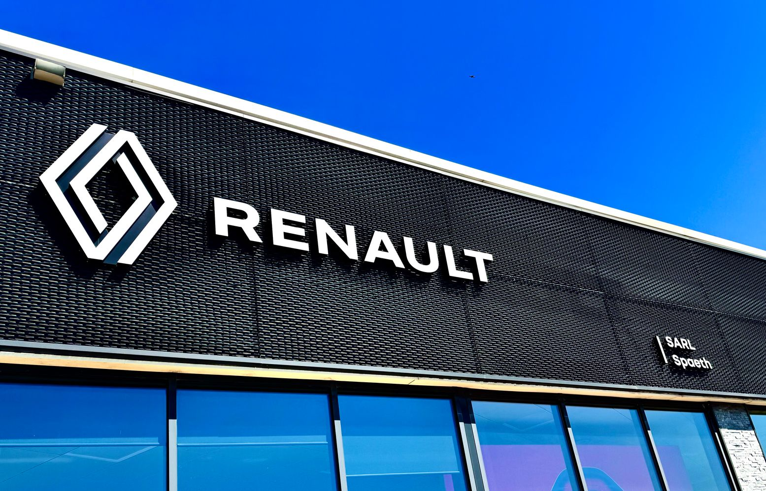 Bâtiment de concession Renault, sous un ciel bleu éclatant.