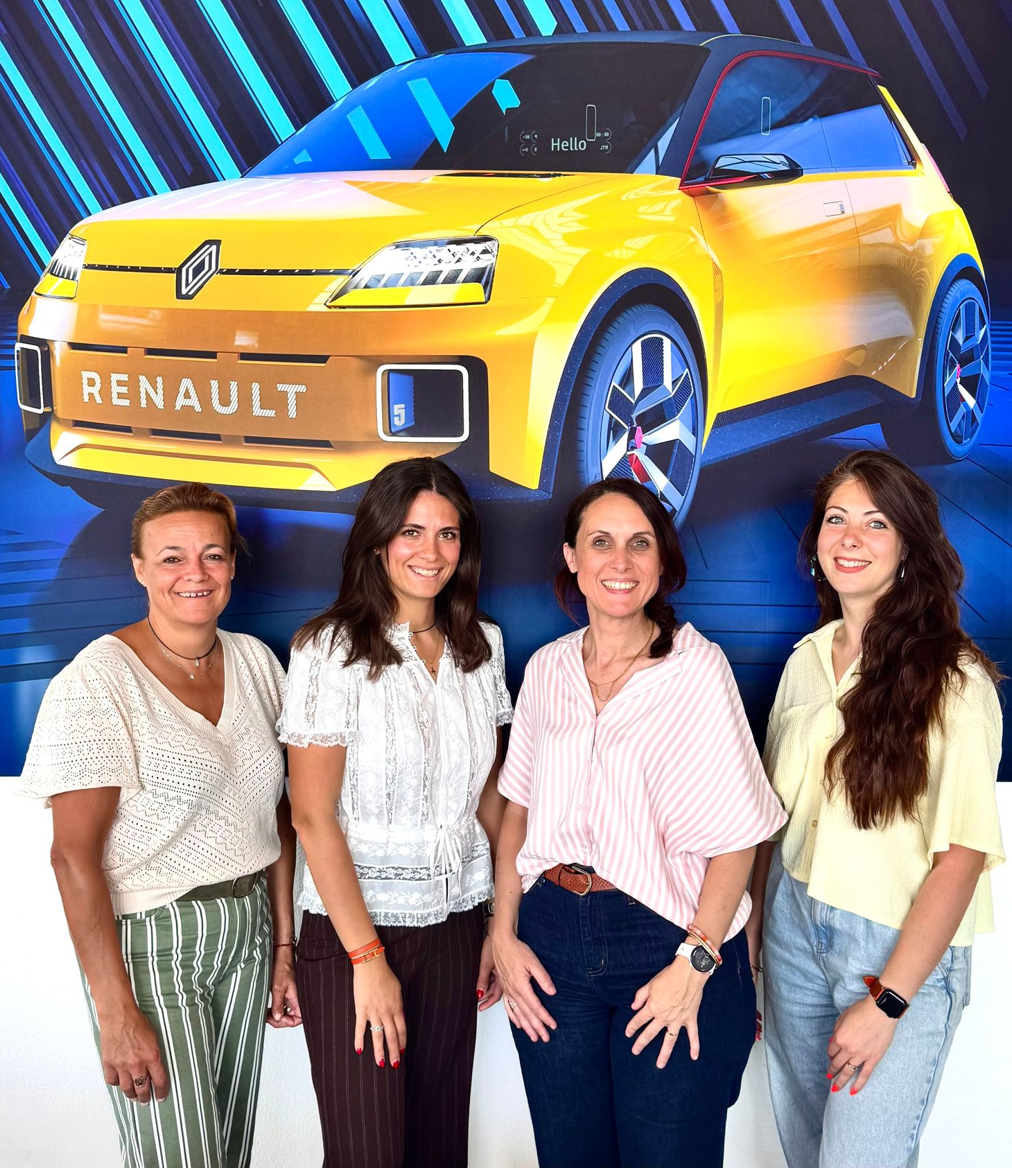 Quatre femmes posent devant l'illustration d'une Renault jaune.