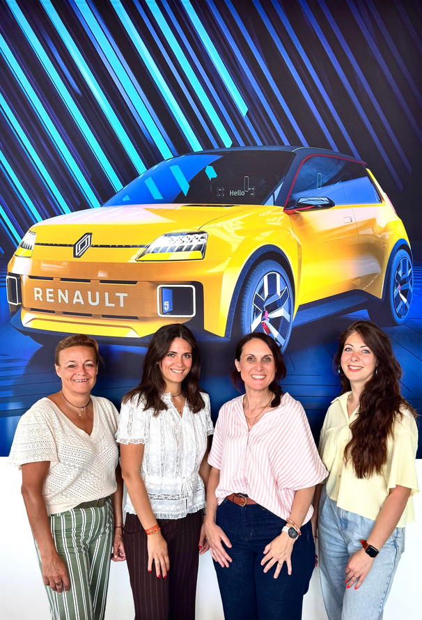 Quatre personnes se tiennent devant une grande affiche présentant une Renault 5 jaune.
