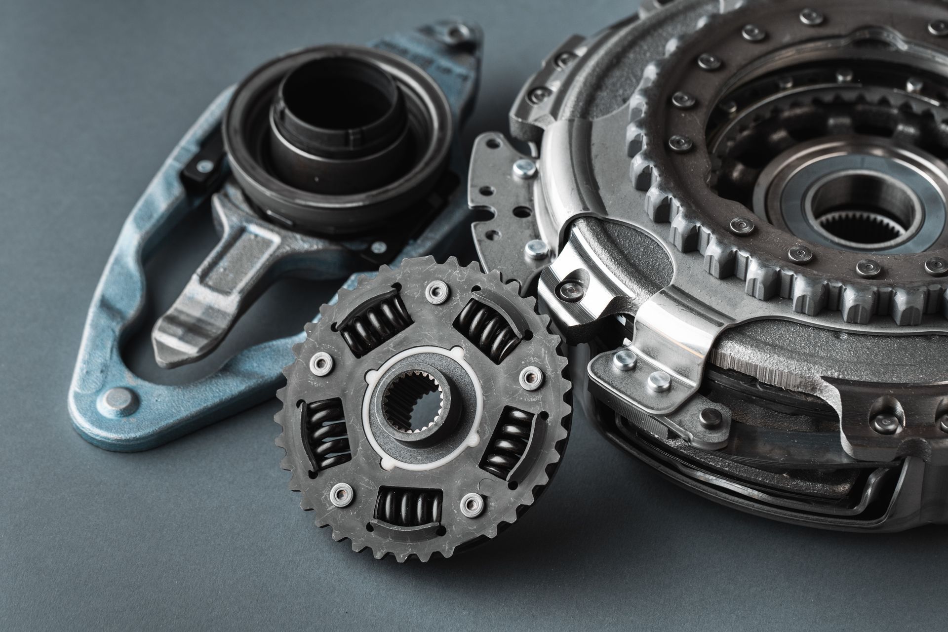 Composants d'embrayage et de transmission d'une voiture sur une surface grise.
