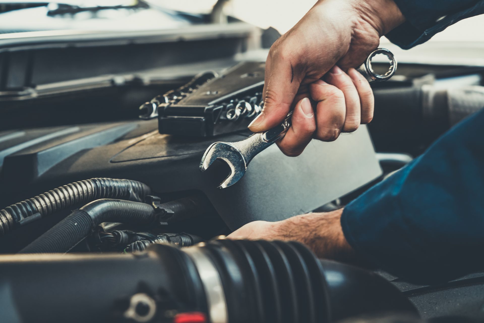 Un mécanicien utilise une clé pour réparer le moteur d'une voiture.