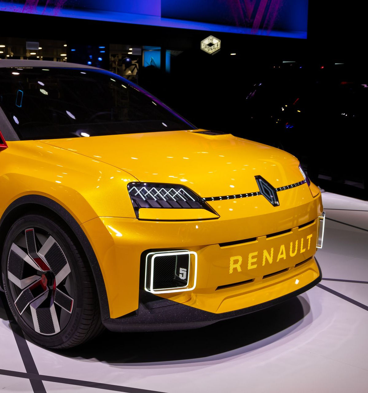 Voiture électrique Renault jaune exposée lors d'un salon automobile.