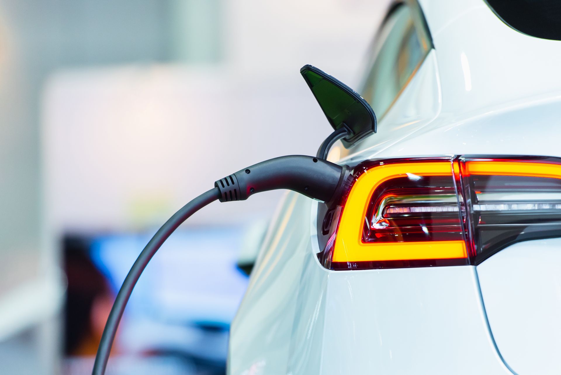 Voiture électrique blanche en charge, avec prise connectée.