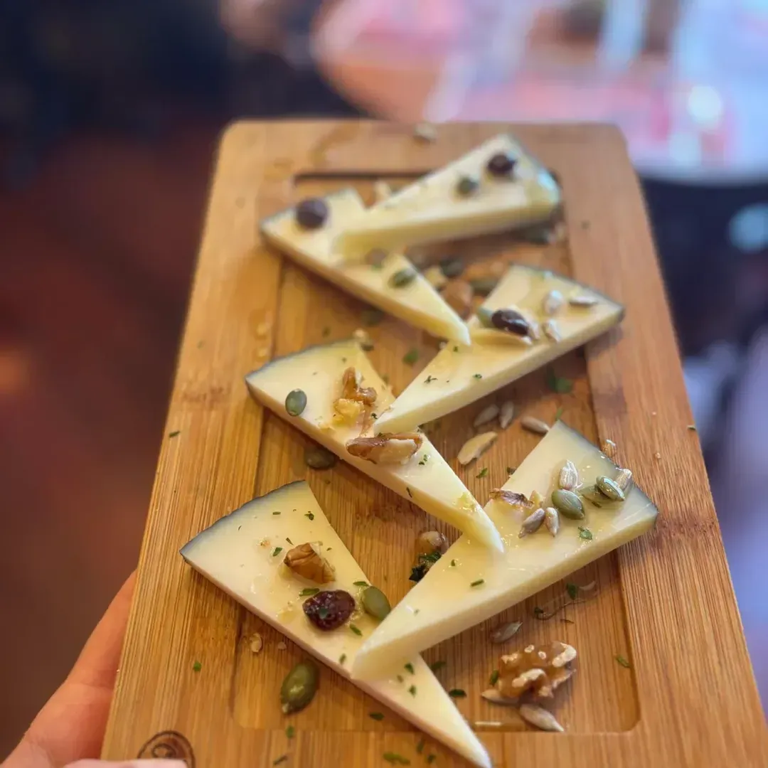 Cinco porciones de queso adornadas con frutos secos, semillas y frutas deshidratadas