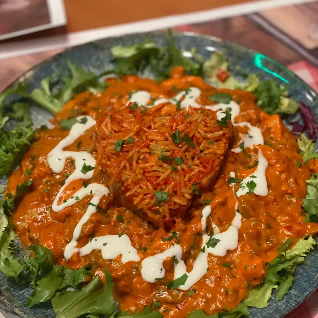 Un montículo de arroz naranja con forma de corazón reposa en un curry rojo cremoso y vibrante
