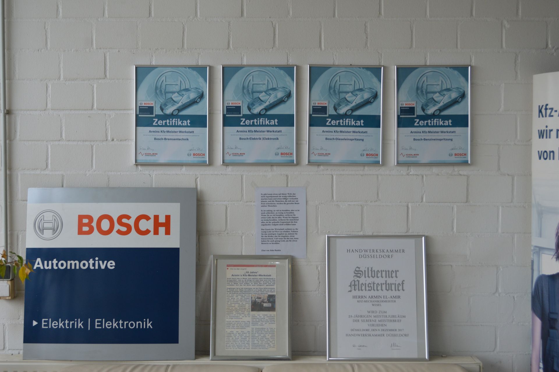 Wandbereich im Empfang mit Bosch-Automotive-Schild, Zertifikaten und Informationsmaterial.