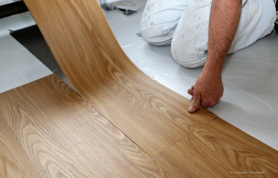 Nahaufnahme eines zotteligen grauen Teppichs auf einem warmen braunen Holzboden.