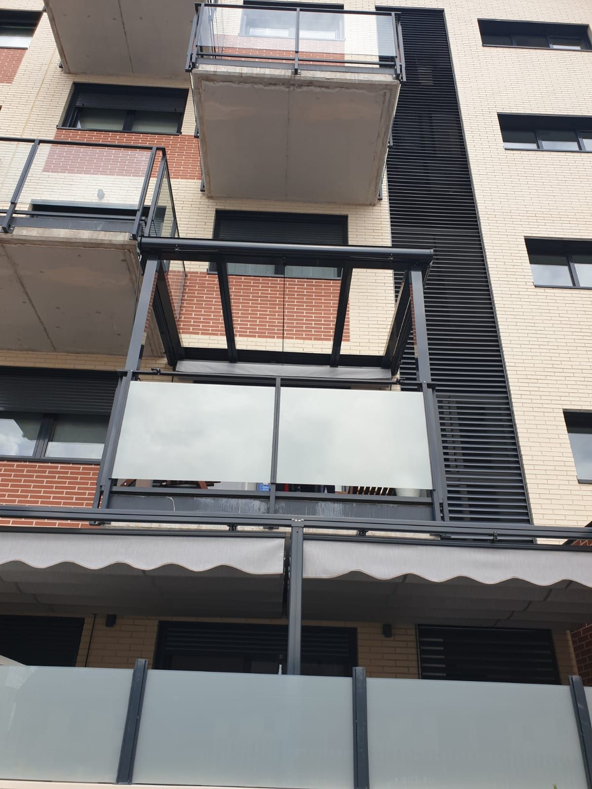 Un balcón en el lateral de un edificio con un toldo blanco.
