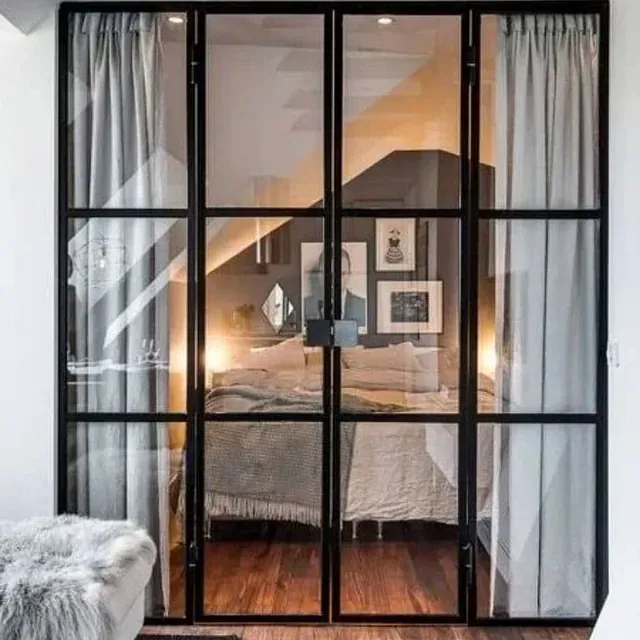 Un dormitorio con una cama y cortinas detrás de una puerta de cristal.