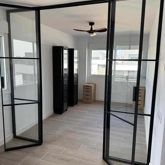 Una habitación con puertas de cristal y un ventilador de techo.