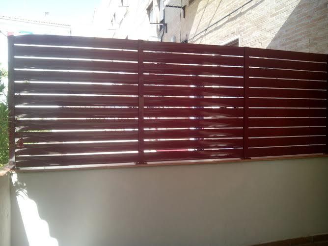 Una pared blanca con una valla de madera delante.