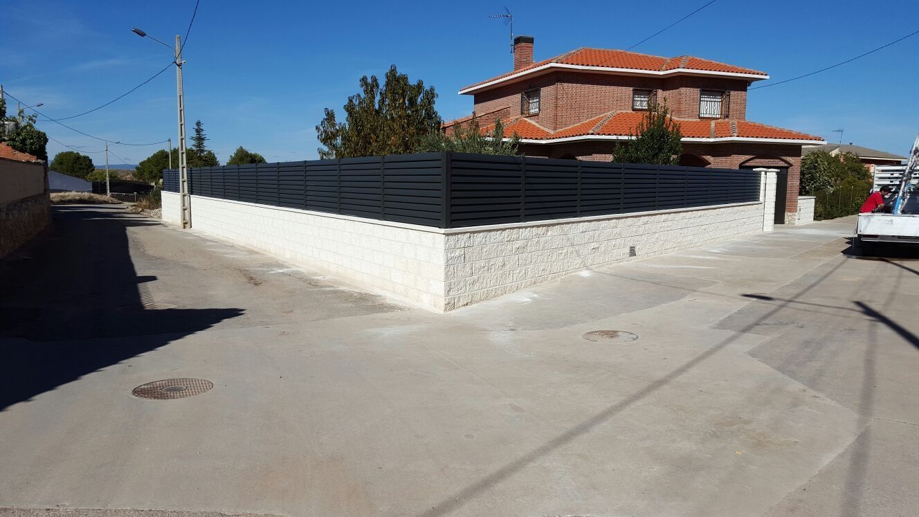 Una casa de ladrillo con una valla negra delante.