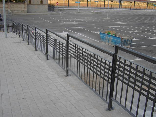 Una valla rodea un estacionamiento vacío con una señal de stop al fondo.