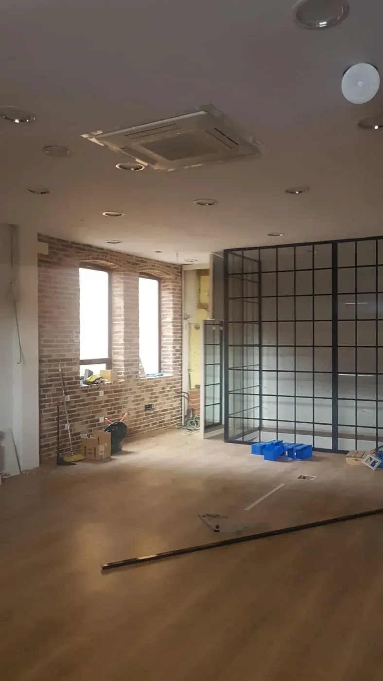 Una habitación vacía con muchas ventanas y un ventilador de techo.