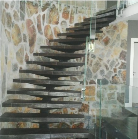 Una escalera con un muro de piedra detrás.