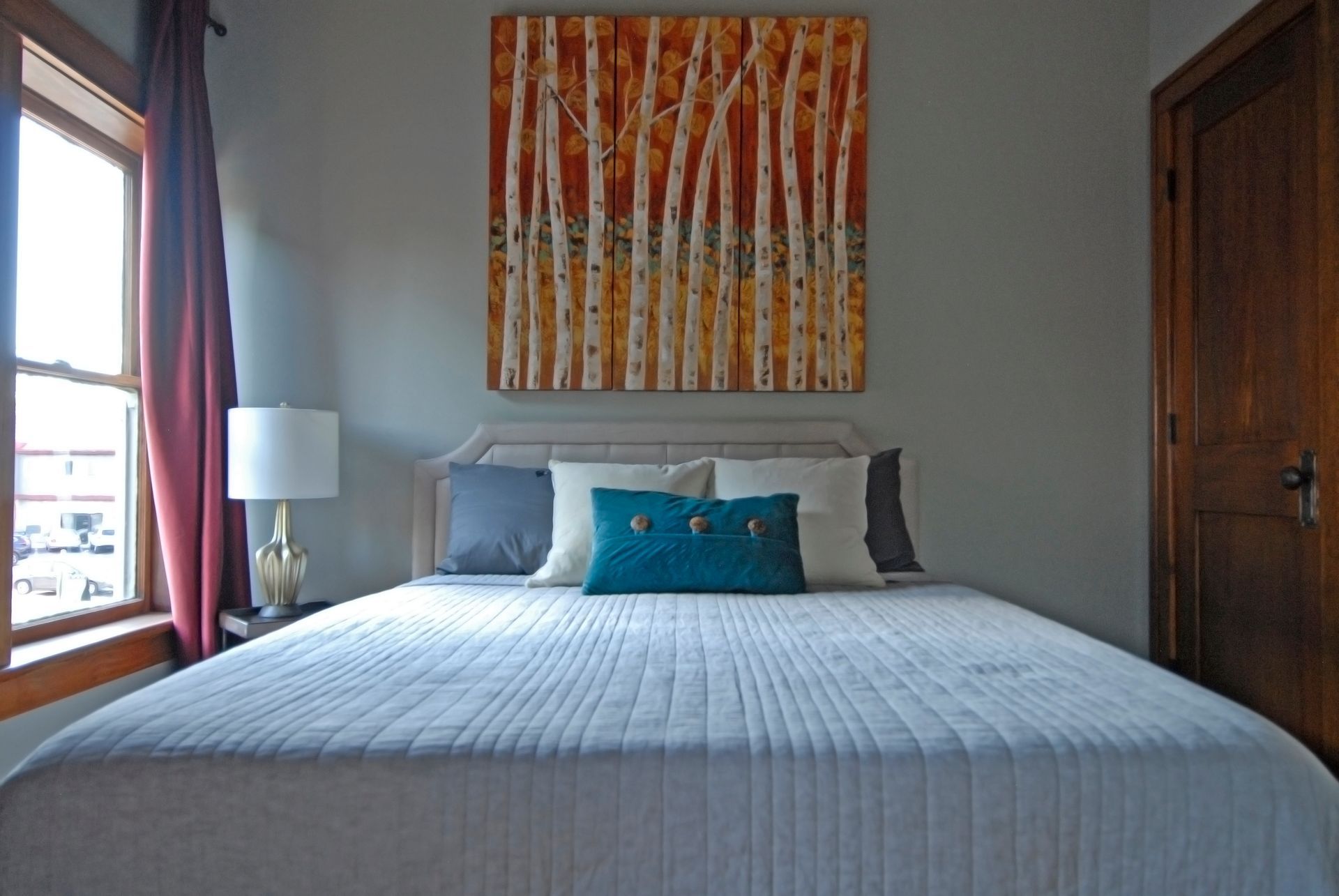 A bedroom with a large bed and a painting on the wall above it