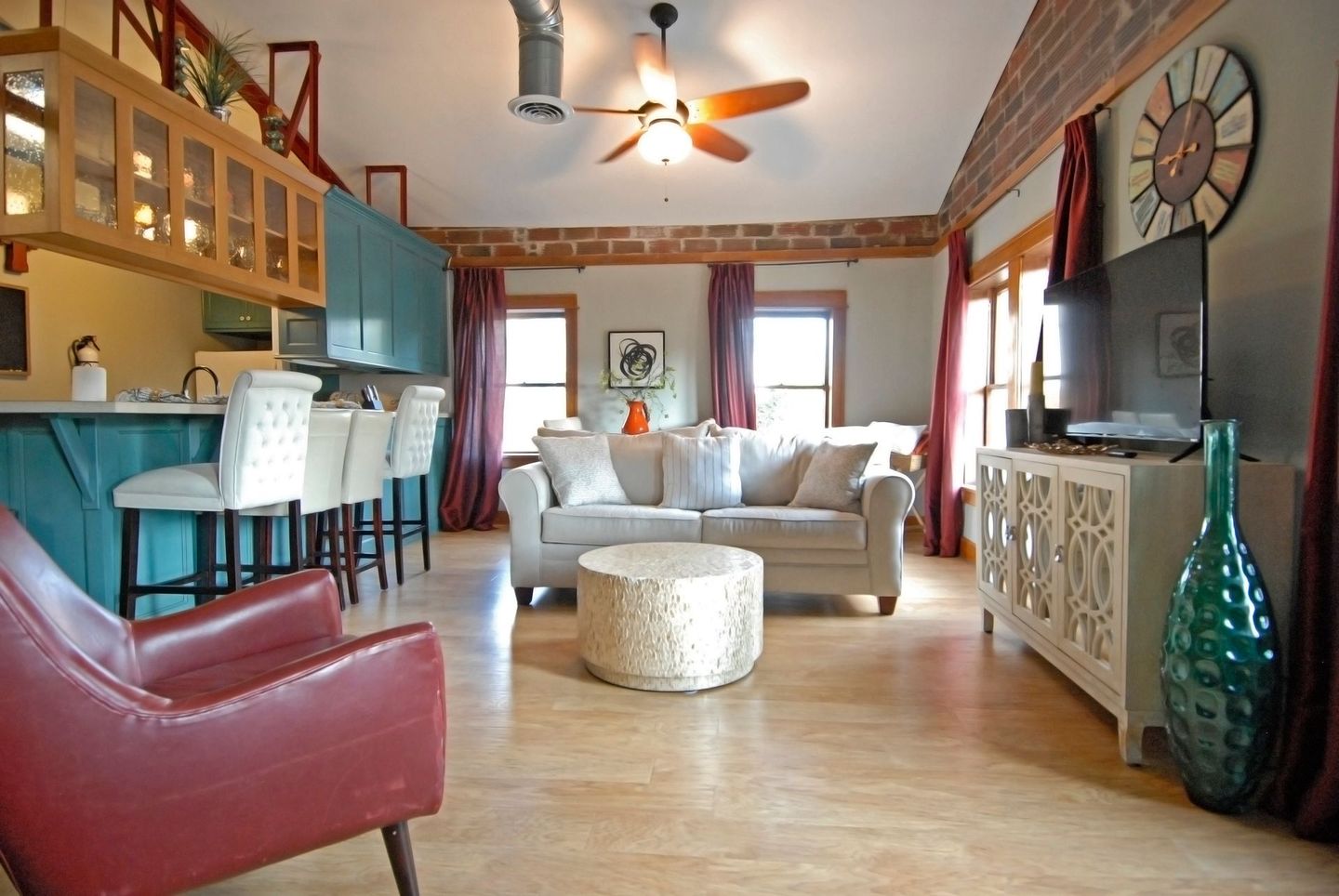 A living room with a couch and chairs and a clock on the wall