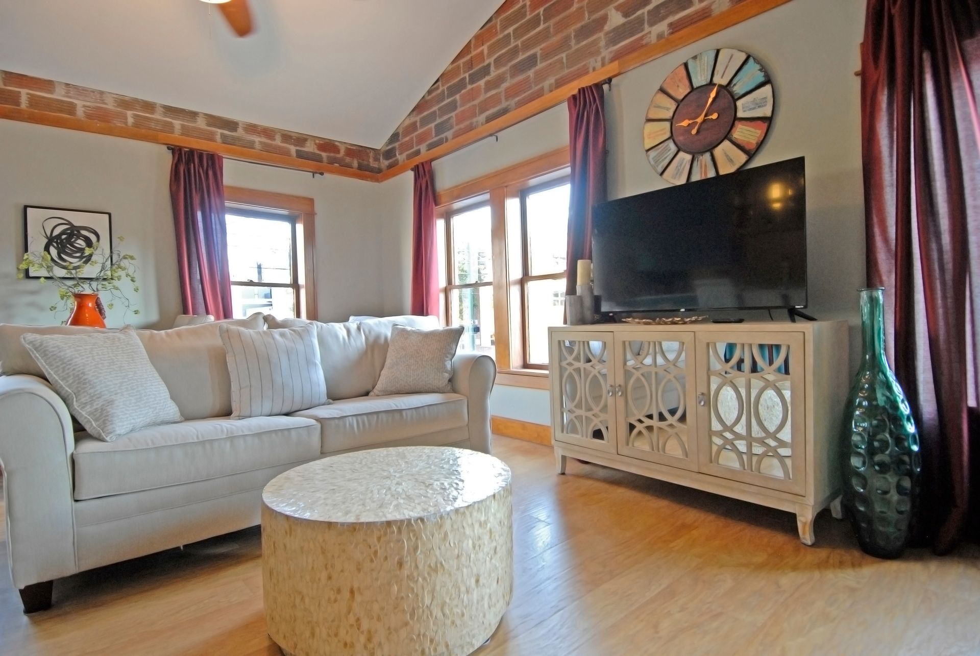 A living room with a couch , table , television and clock on the wall.