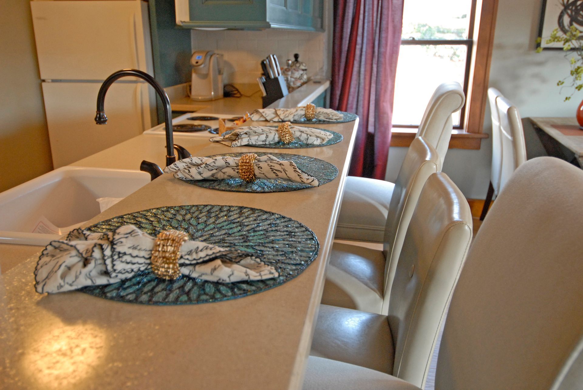 A kitchen with a sink , chairs , and a table with napkins on it