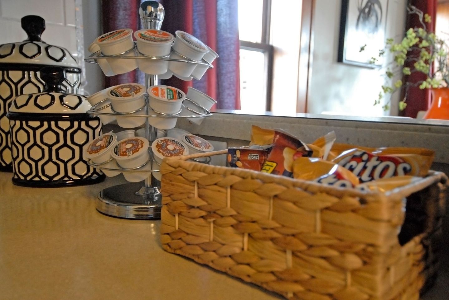 A wicker basket filled with chips sits on a counter next to a coffee pod holder.