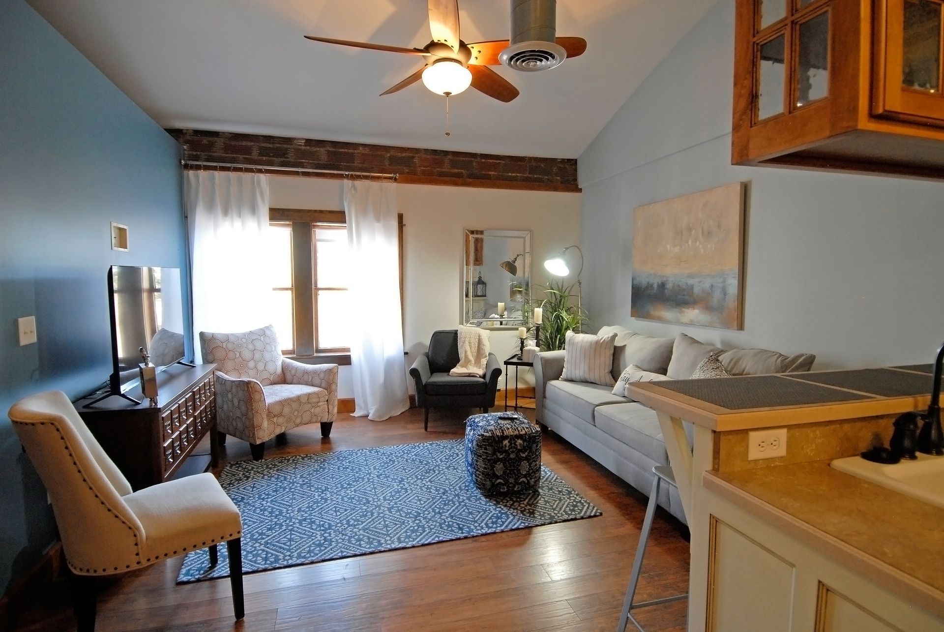 A living room with a couch and chairs and a ceiling fan