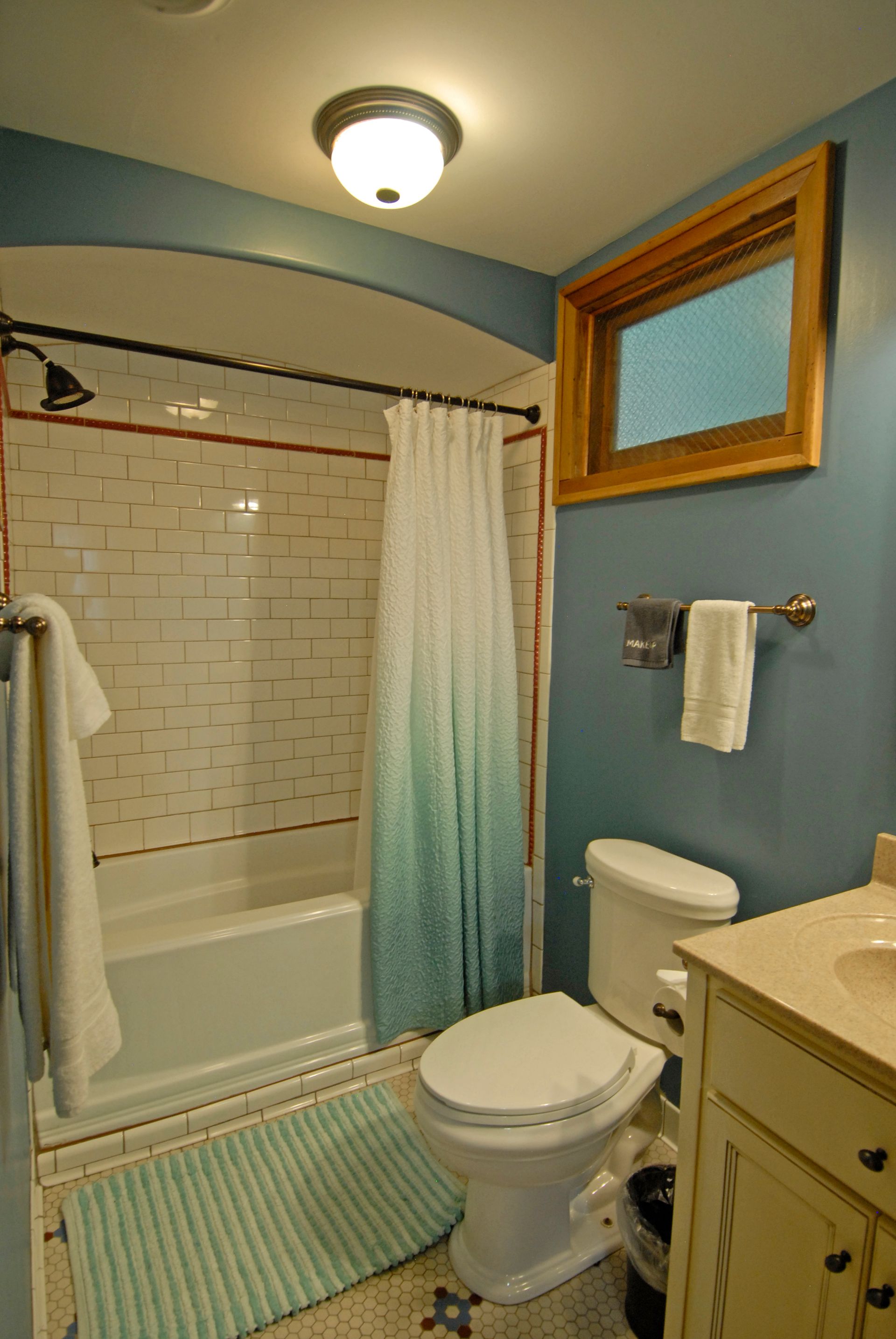 A bathroom with a toilet a bathtub and a window