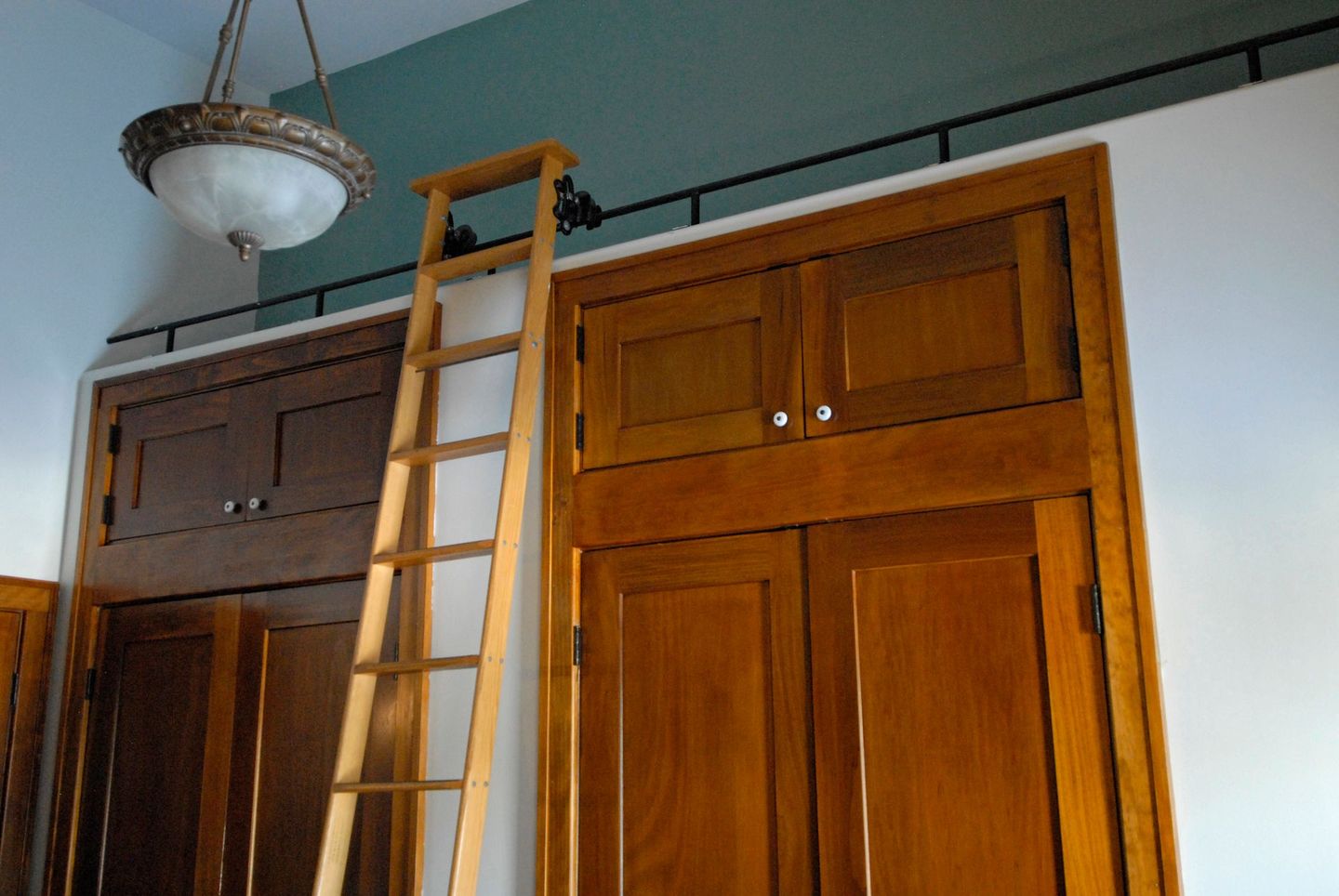 A wooden ladder is hanging from the ceiling above a closet