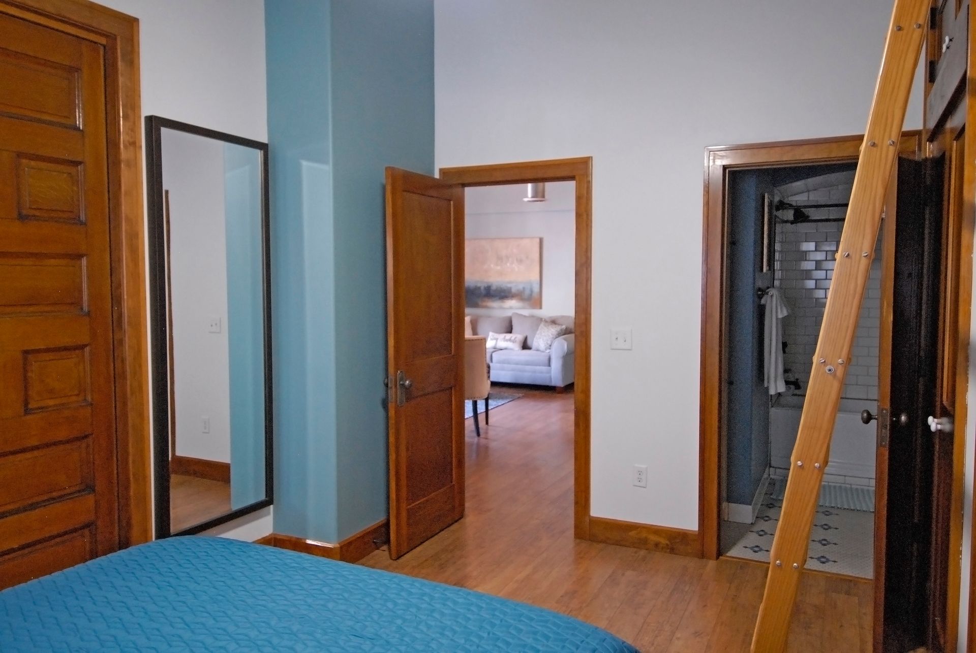 A bedroom with a blue blanket and a large mirror