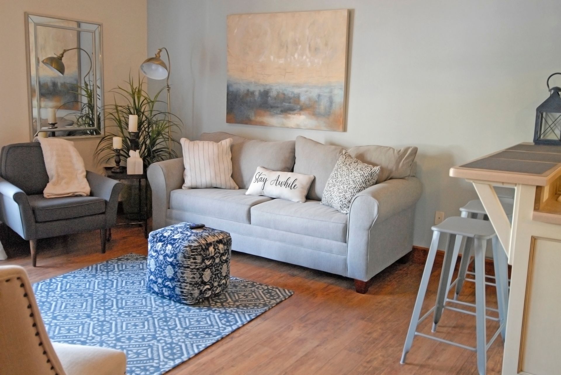 A living room with a couch , chairs , ottomans and a table.