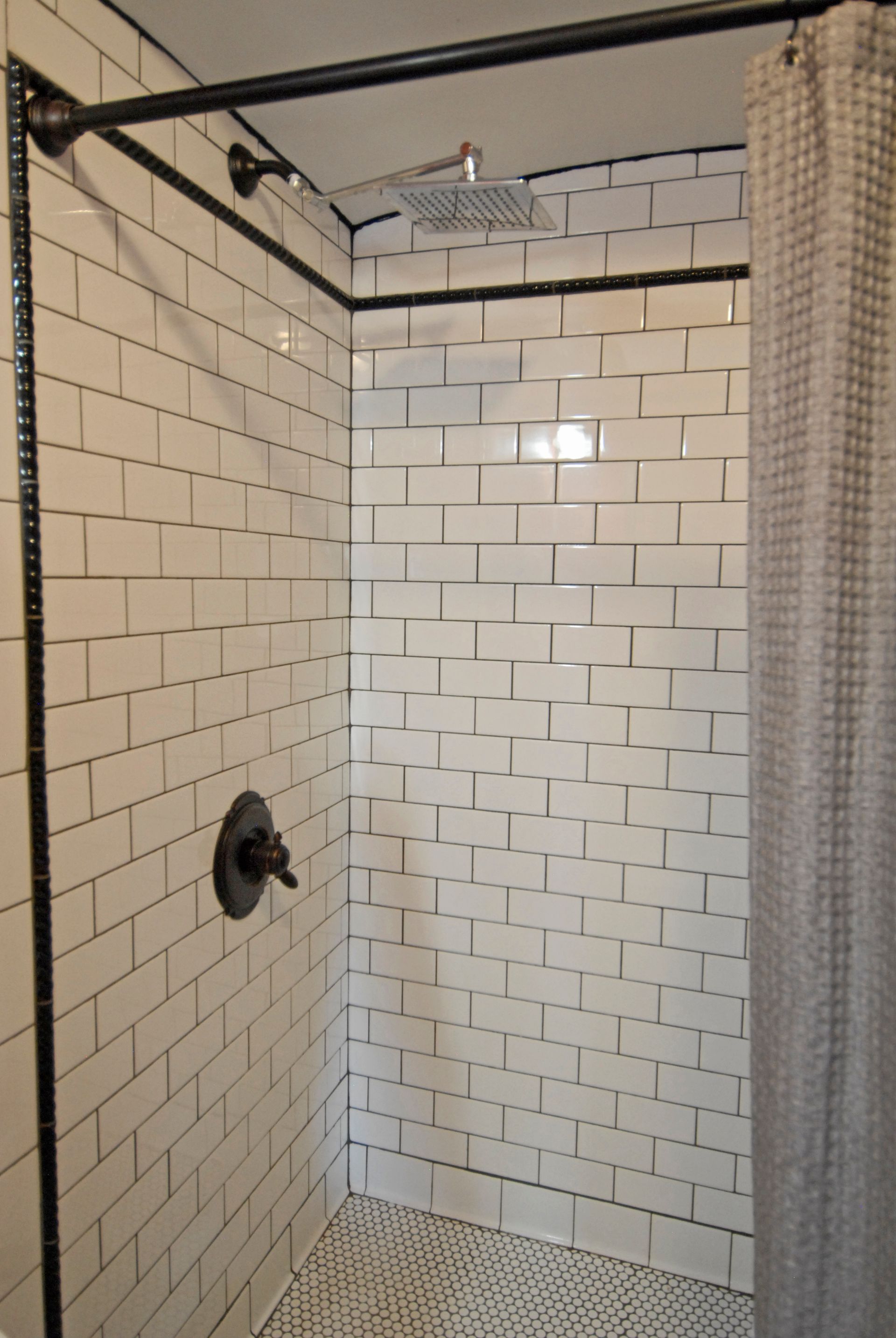 A shower with white tiles and a shower head