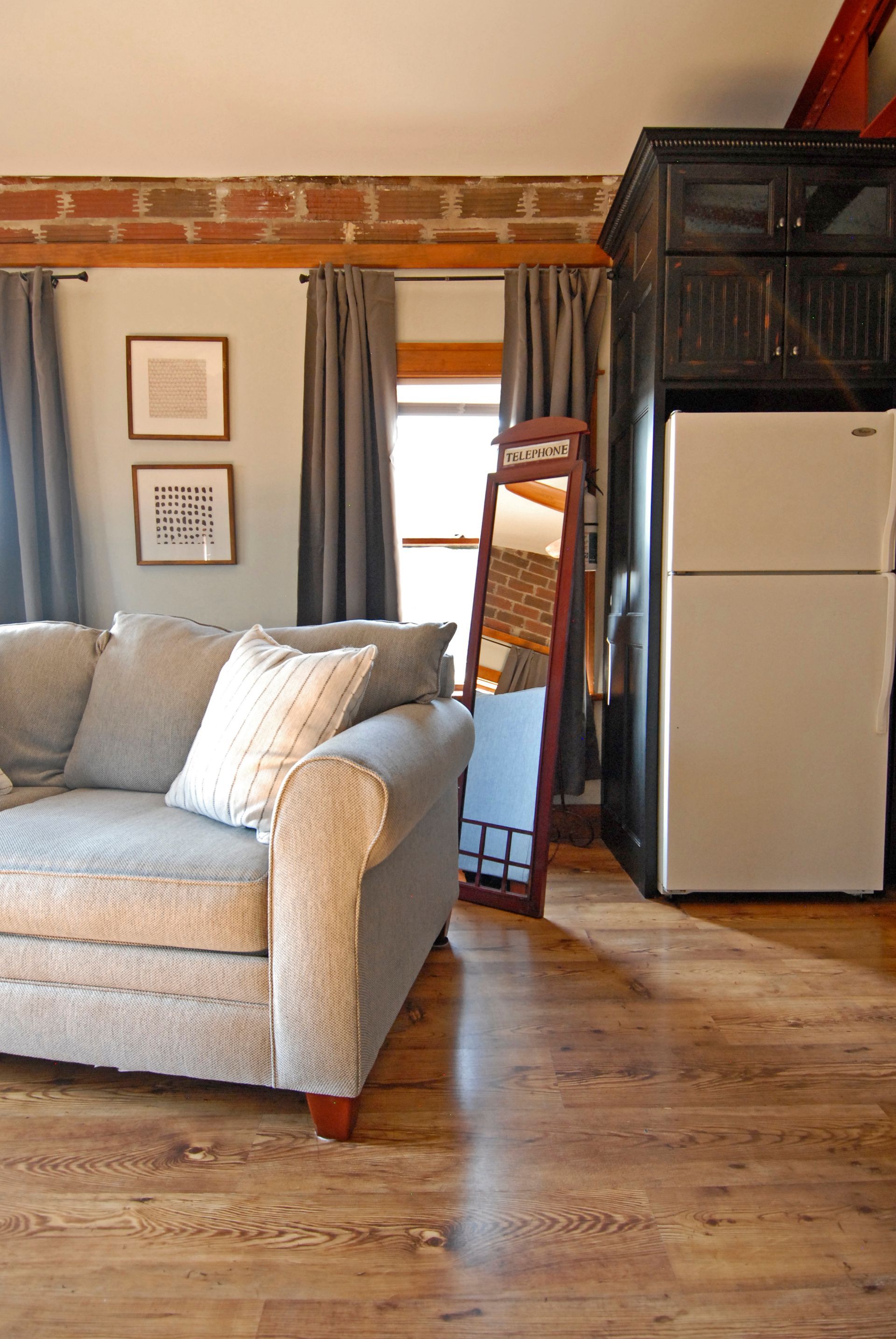 A living room with a couch a refrigerator and a mirror