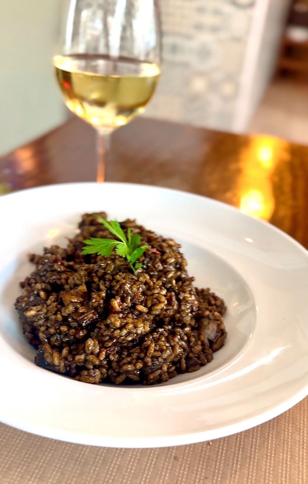 Aceitunas verdes en un bol blanco, con alcaparras en un plato pequeño y pan en una esquina.