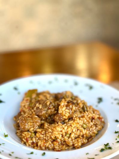 Trozos de papa dorados en un recipiente azul, cubiertos con salsa rosa y guarnición de pimiento rojo.