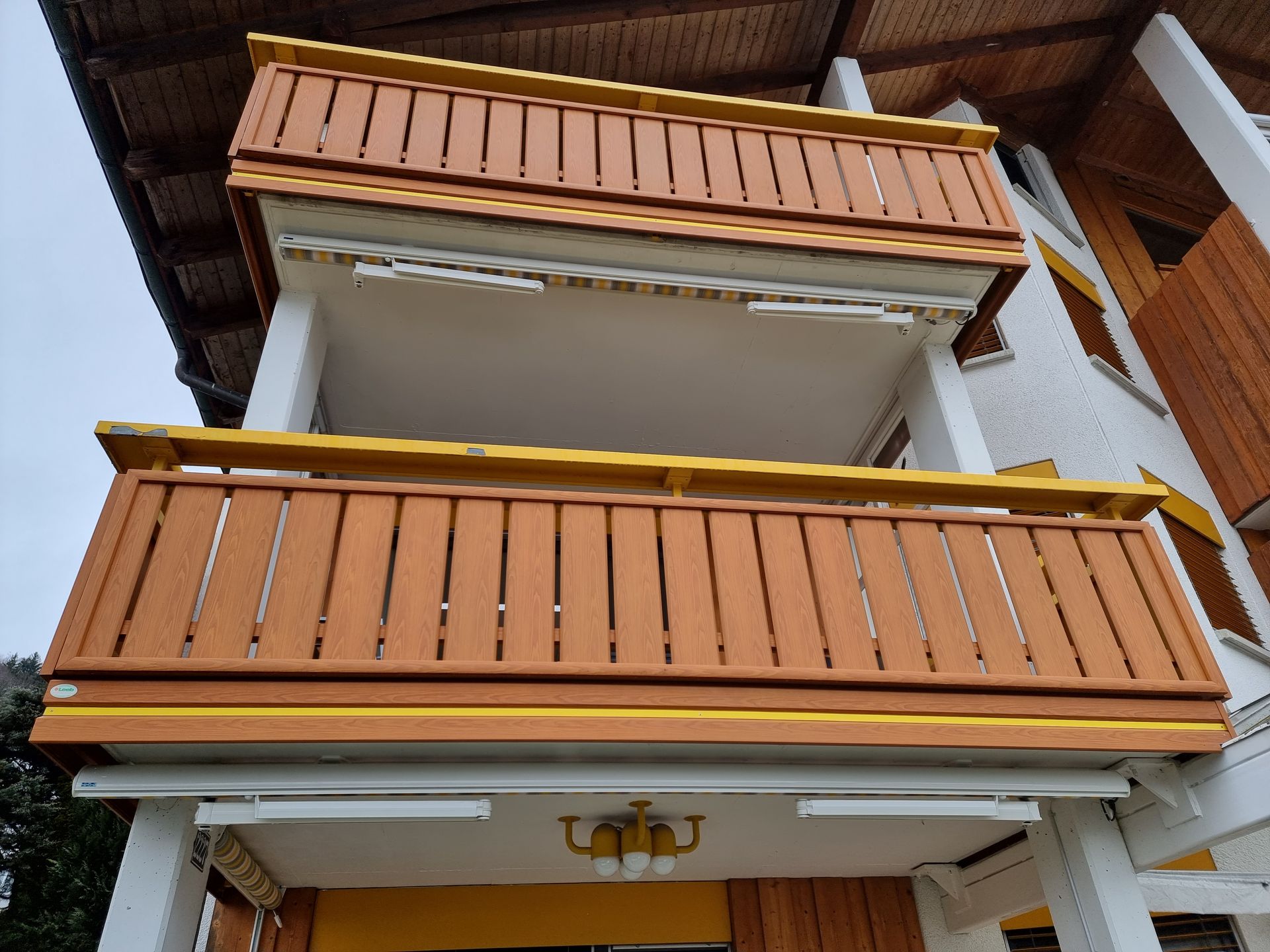 Zweistöckiges Gebäude mit braunen Holzbalkonen.