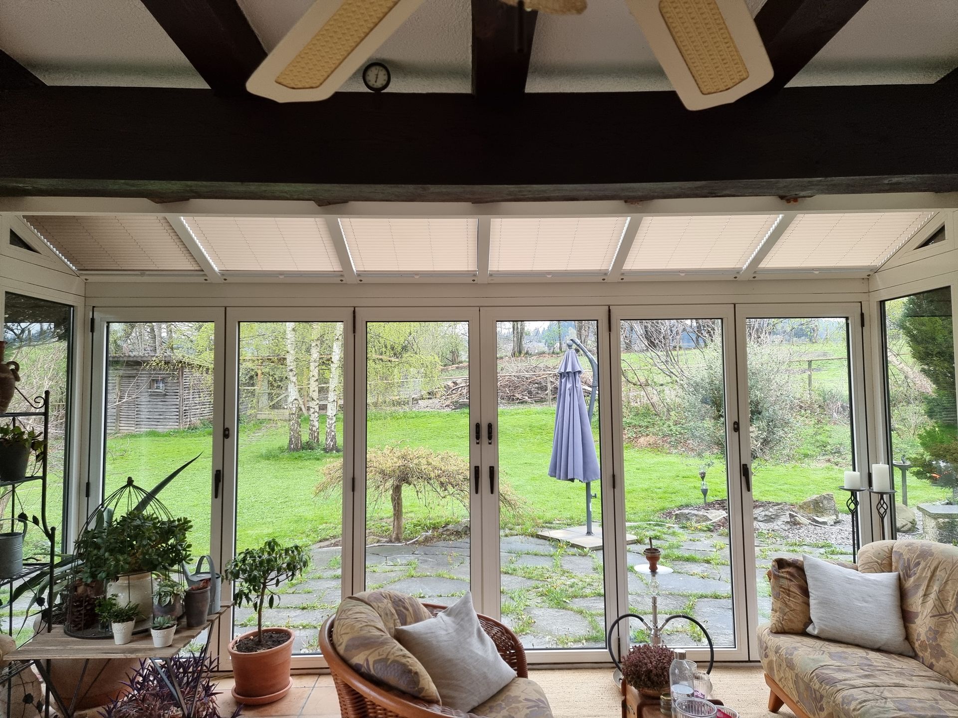 Wintergarten mit Glastüren und Blick auf einen grünen Garten. Inneneinrichtung.